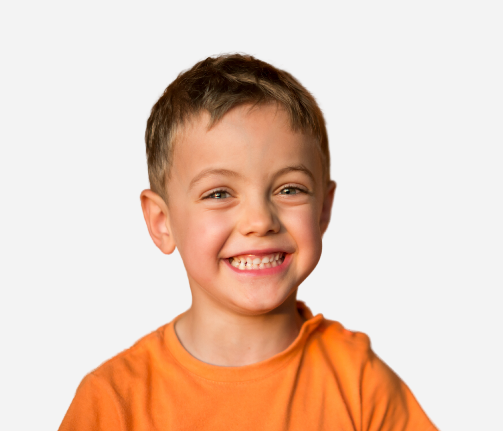 A smiling young child with short hair wearing an orange shirt.