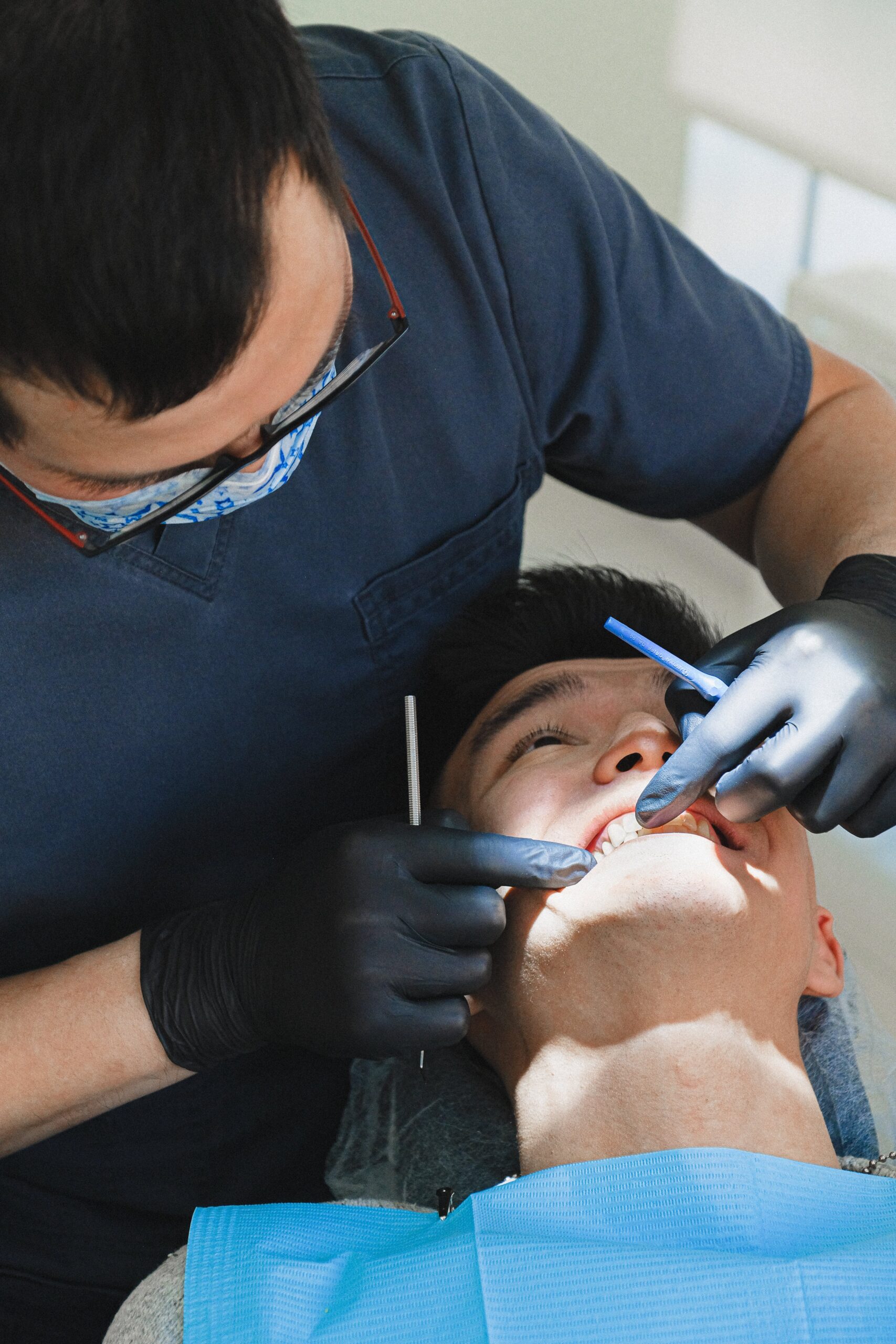 A dentist is treating a patient's teeth while the patient lies in a dental chair.